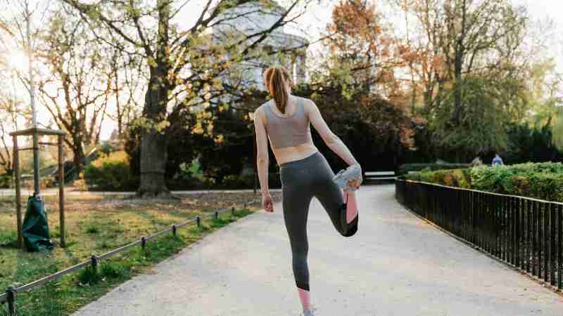 A woman performs a stretching exercise in a park setting, showcasing fitness and a healthy lifestyle., tags: krachttraining - pexel