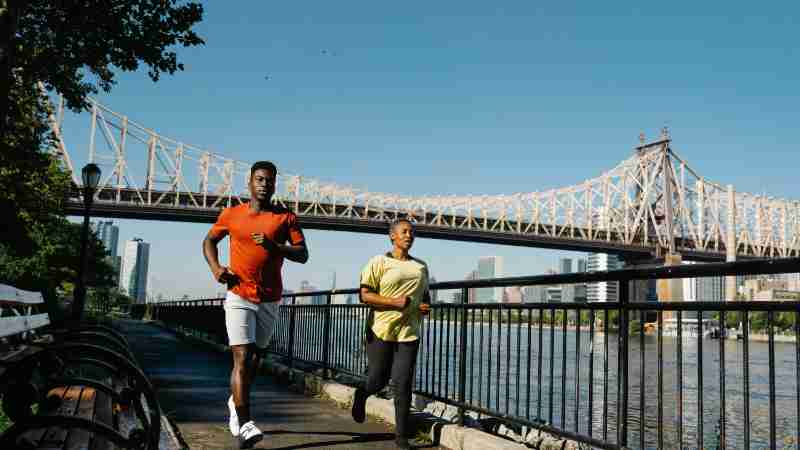 Two adults jogging together by the waterfront near Queensboro Bridge in NYC., tags: de - pexel